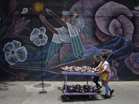 Two people carry flowers outside the Jamaica Market in Mexico City where dozens of people came to buy flowers and gifts for Mother's Day, wh...