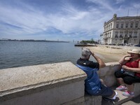 Several people are seen resting near the Tejo river bank, in the neighborhood of Baixa, Lisbon. 02 May 2023. (