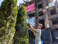 A man trims a tree in front of bombarded and burnt block of flats as reconstruction plan for the destroyed neighbourhood started in Irpin, K...