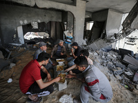 Palestinians eat amidst the rubble of their house in Gaza City, on May 14, 2023, following a ceasefire ending five days of deadly fighting b...