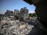 Palestinians inspect their belongings amidst the rubble of their house in Gaza City, on May 14, 2023, following a ceasefire ending five days...