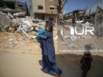 A Palestinian woman walks with her children amidst the rubble of her house in Gaza City, on May 15, 2023, following a ceasefire ending five...