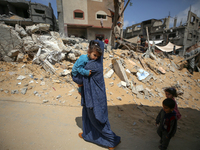 A Palestinian woman walks with her children amidst the rubble of her house in Gaza City, on May 15, 2023, following a ceasefire ending five...