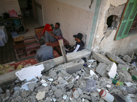Palestinian men sit amidst the rubble of their house in Gaza City, on May 15, 2023, following a ceasefire ending five days of deadly fightin...