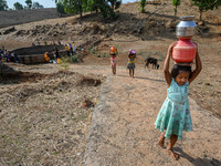 Children carry pitchers full of water which they have collected from a dry well, at Koli pada village in the western Indian state of Maharas...