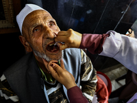 An elderly Muslim receive drops before leaving for Hajj during Hajj Vaccination program at SDH Sopore District Baramulla Jammu and Kashmir I...
