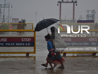 An indian woman with her child,walks on a road during a cold and rainy day in Allahabad on January 19,2016.A cold wave over northern India h...
