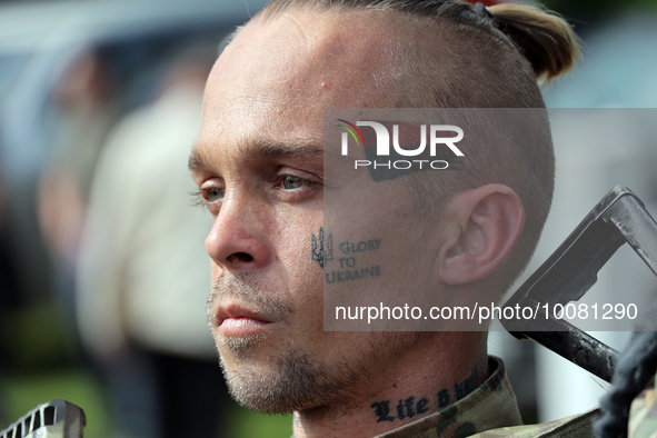 NORTHERN UKRAINE - MAY 24, 2023 - A fighter with a red-black flag, tryzub and the 'Glory to Ukraine' phrase tattoed on his face is pictured...