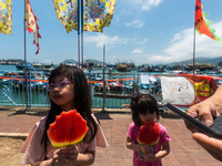 

Two young girls are eating frozen watermelon in the scorching heat of Cheung Chau, while watching the parades for the bun festival, in Hon...