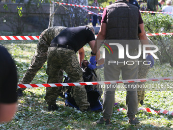Ukrainian  forensic specialists carry a body of a woman killed during a Russian missile overnight attack outside a damaged building of healt...