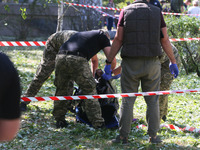 Ukrainian  forensic specialists carry a body of a woman killed during a Russian missile overnight attack outside a damaged building of healt...