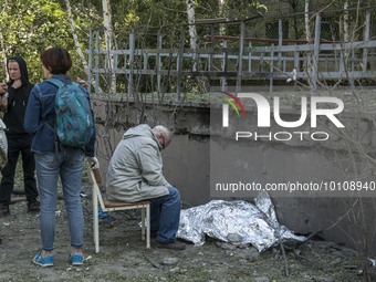 A man sits next to the body of his granddaughter who was killed during a Russian missile strike in Kyiv, Ukraine June 1, 2023 (