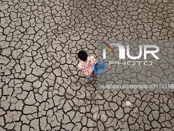 A young man braves the drought, trekking to a reservoir to collect water, in Khulna, Bangladesh, on May 14, 2023. (