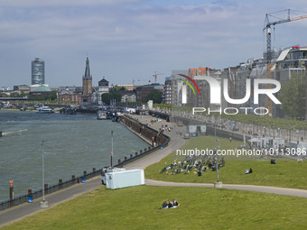 General view during a sunny day of the waterfront of the city of Düsseldorf with the parks and buildings alongside and Rhine river bank from...