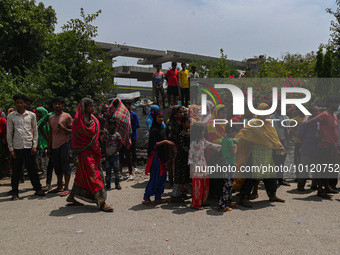 People stand on the road outside the slum cluster of Jahangirpuri area where a fire had broke out as the dousing operation was underway in N...