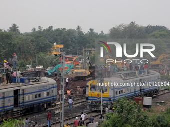 Railway workers and NDRF people are seen at the Coromandel express train accident site as they are busy in the derailed coaches removing wor...