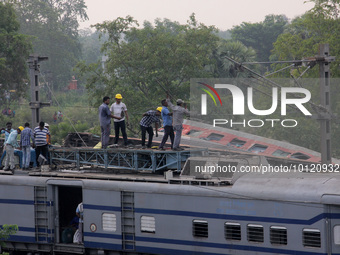Railway workers and NDRF people are seen at the Coromandel express train accident site as they are busy in the derailed coaches removing wor...