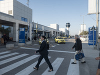 Passengers holding baggage are seen walking outside the departures building pulling their luggage. People who travel spotted inside the depa...