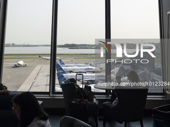 Silhouette of passenger sitting in the airport terminal over JetBlue Airbus A320 series passenger aircraft of the low cost airline as seen a...