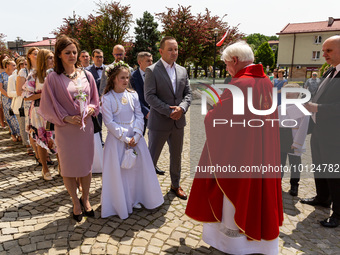 Children dressed in white dress and their parents receive blessings from a priest in front of the St Mary Magdalene Church in Tychy, Poland...
