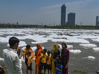 A family poses for a photograph on the banks of river Yamuna covered with toxic foam caused by industrial discharge, on the World Environmen...