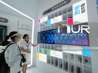 BEIJING, CHINA - JUNE 5, 2023 - Visitors look at the evolution of mobile phones at the China Telecom exhibition area during the 31st China I...