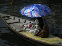 Passengers cross the river Buriganga as they hold an umbrella to prevent suns heat during a heat wave in Dhaka, Bangladesh, May 06, 2023....