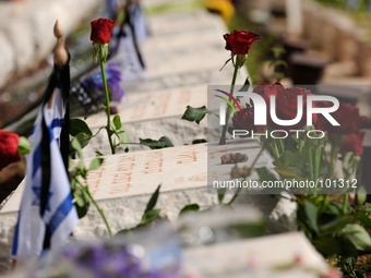 TEL AVIV, ISRAEL - MAY 05: Israeli flags and flowers are placed over graves of a fallen Israeli soldiers at the military cemetery Kiryat Sha...