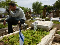TEL AVIV, ISRAEL - MAY 05: An Israeli soldier reacts as he sits by the grave of a fallen Israeli soldier at the military cemetery Kiryat Sha...