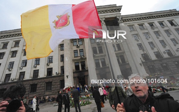 A man flies the Odessa flag in front of the Trade Union building.  Hundreds went to view the damage inside and place memorials throughout th...