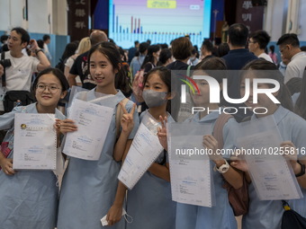 Students holding their secondary school allocation result posing for a photo at a school hall on July 11, 2023 in Hong Kong, China. Primary...