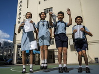 Students holding their secondary school allocation result jumping in the air while posing for a photo on July 11, 2023 in Hong Kong, China....