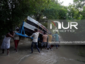 Locals along with the State Disaster Response Force (SDRF) personnel unload boats to evacuate stranded residents from low-lying areas, after...
