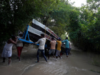 Locals along with the State Disaster Response Force (SDRF) personnel unload boats to evacuate stranded residents from low-lying areas, after...