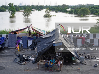 People evacuated from low-lying areas are seen in makeshift shelters along a road, after being displaced by the rising water level of river...