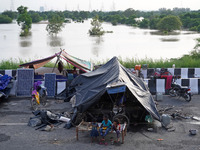 People evacuated from low-lying areas are seen in makeshift shelters along a road, after being displaced by the rising water level of river...