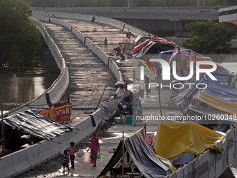 People evacuated from low-lying areas are seen in makeshift shelters on an under-construction flyover, after being displaced by the rising w...
