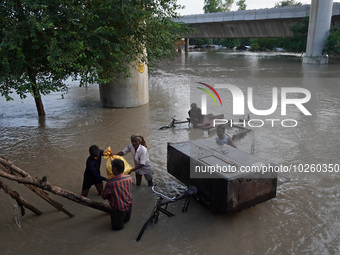 People with their belongings wade through the flooded waters in low-lying areas, after being displaced by the rising water level of river Ya...