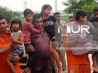 Members of the National Disaster Response Force (NDRF) evacuate stranded children from a flooded neighborhood, amid a rise in the water leve...