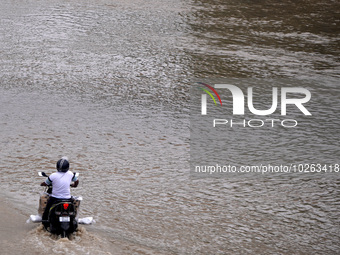 A motorist makes his way through a flooded carriageway, after a rise in the water level of the river Yamuna due to heavy monsoon rains in Ne...