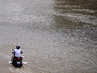 A motorist makes his way through a flooded carriageway, after a rise in the water level of the river Yamuna due to heavy monsoon rains in Ne...