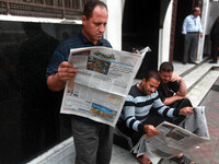 Palestinian men read the Al-Quds Newspaper in Gaza city, on May 06, 2014. Palestinian government in Gaza strip allowed the redistribution of...