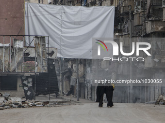 Two women, one carrying a child and they walking near one of curtains  on Bustan Alqasr district in Aleppo city on 1st February 2016.
(