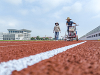  Construction workers mark the plastic runway at the construction site of Fuguo Road Middle School in Lianyungang, Jiangsu province, China,...