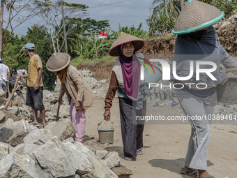 Women carries a bucket of sand and stone as they help villagers to renovate a broken village road at Kebumen, Central Java, Indonesia on Aug...