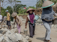Women carries a bucket of sand and stone as they help villagers to renovate a broken village road at Kebumen, Central Java, Indonesia on Aug...