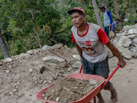 A man pulls a crate full of big stone as he helps villagers to renovate a broken village road at Kebumen, Central Java, Indonesia on August...
