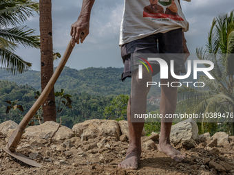 A man holds a hoe, as he helps villagers to renovate a broken village road at Kebumen, Central Java, Indonesia on August 20, 2023.  (