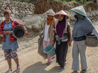 Women walks in a broken road as they help villagers to renovate a broken village road at Kebumen, Central Java, Indonesia on August 20, 2023...