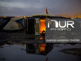 at night, a man is resting lying in his hut surrounded by water in the heart of the jungle, in Calais, northern France on February 6, 2016 ....